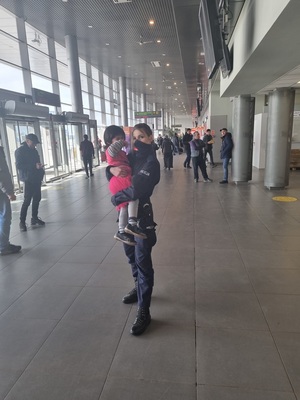 policjantka w mundurze trzyma na rękach dziecko, stoją w terminalu lotniska