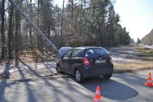czarny samochód, który uderzył w słup energetyczny, obok pojazdu pomarańczowe pachołki