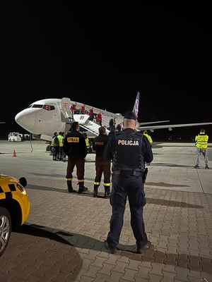 policjant obserwujący piłkarzy wysiadających z samolotu