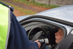 mężczyzna w pojeździe poddawany badania alkomatem przez policjanta