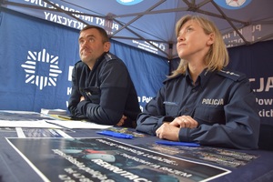 Policjantka i policjant przy niebieskim stole wewnątrz niebieskiego namiotu