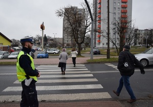 policjant obserwujący przejście dla pieszych, przez które przechodzą ludzie