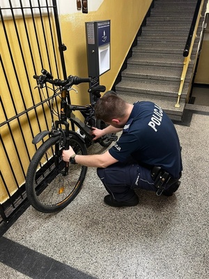 policjant sprawdzający odzyskany rower w korytarzu komisariatu