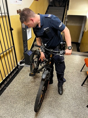 policjant sprawdzający odzyskany rower w korytarzu komisariatu
