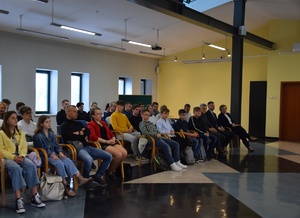 osoby siedzące na krzesłach w sali konferencyjnej
