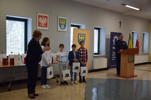 uczestnicy konkursu z nagrodami, obok nich starosta tarnogórski, w dalszym planie policjant przy mównicy