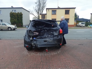 rozbity tył czarnego samochodu, w tle zabudowania