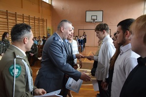 przedstawiciel policji i władz powiatowych wręczający uczniom certyfikaty