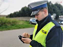 policjant w niebieskim mundurze, kamizelce odblaskowej i białej czapce