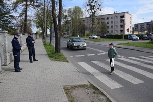 policjanci obserwujący przejście dla pieszych, przez które przechodzi osoba