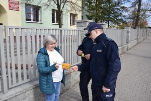 policjanci wręczają kobiecie opaskę odblaskową