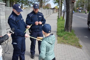 policjanci wręczają dziecku opaskę odblaskową