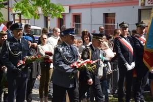 komendant powiatowy z wiązanka kwiatów, w tle uczestnicy uroczystości