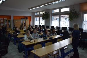 szkolna klasa, uczniowie w ławkach, przed nimi policjantka