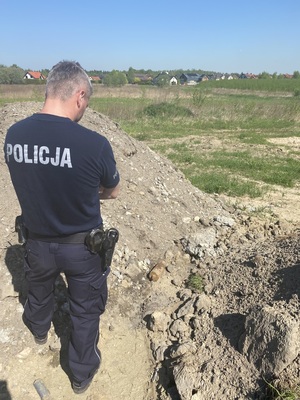 policjant w mundurze obserwujący znaleziony pocisk