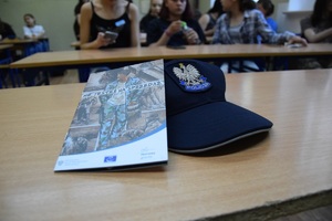 policyjna czapka na blacie ławki, obok broszura z napisem <nie jesteś na sprzedaż>