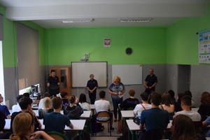 szkolna sala, w ławkach uczniowie, na przeciwko nich policjanci i dyrektor szkoły