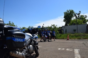 policyjny motocykl, w tle uczestnicy zawodów zmierzający do punktu zmagań
