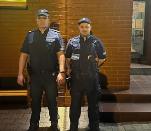 policjanci w mundurach przed budynkiem komisariatu
