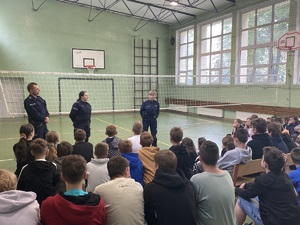 policjanci stojący przed uczniami w sali gimnastycznej