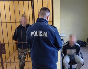 zatrzymani mężczyźni skuci kajdankami, obok nich policjant w mundurze