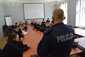 uczniowie w sali, przed nimi policjant