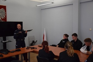 policjant  prezentujący uczniom broń