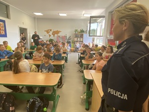 policjantka prowadząca spotkanie z dziećmi w sali lekcyjnej, dzieci siedzą w ławkach