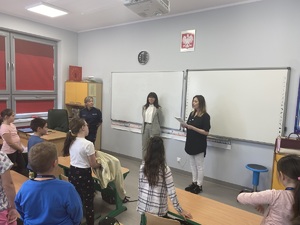 policjantka, pracownik inspektoratu pracy i nauczyciel szkoły podstawowej w centralnej części klasy, stoją przed uczniami