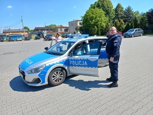 policjant przy radiowozie, w którym siedzą dzieci