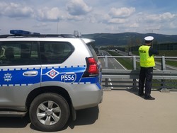 policjant przy radiowozie, w tle jezdnia drogi
