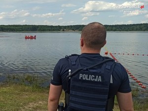 policjant obserwujący akwen wodny, na którym pływają dwie motorówki