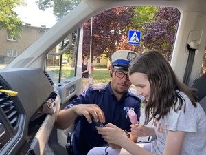 dziewczynka siedząca w radiowozie, obok niej policjant