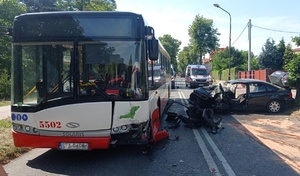 autobus miejski z roztrzaskanym przodem, obok niego samochód osoby z uszkodzonym przodem i bokiem