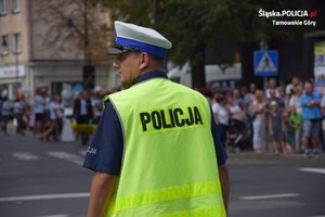 policjant stojący przy jezdni, w tle osoby