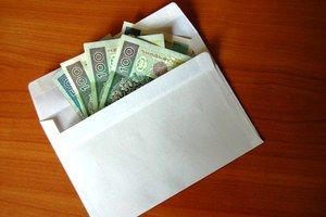 biała koperta z której wystają banknoty