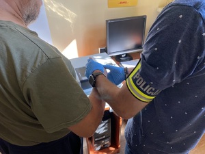 policjant z opaską z napisem &lt;policja&gt; w trakcie czynności z zatrzymanym