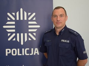 dzielnicowy przy banerze z napisem policja
