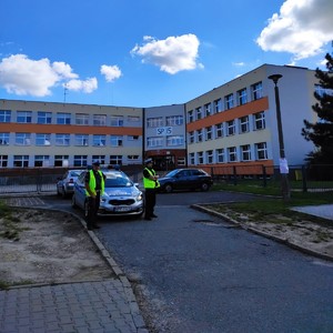 policyjny radiowóz a w tle szkoła