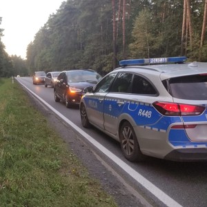 oznakowany radiowóz a  tle czarny samochód