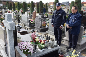 policjant umundurowany wraz z kapelanem przy grobie