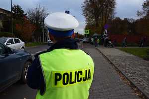 Umundurowany policjant stojący tyłem w kamizelce z napisem Policja