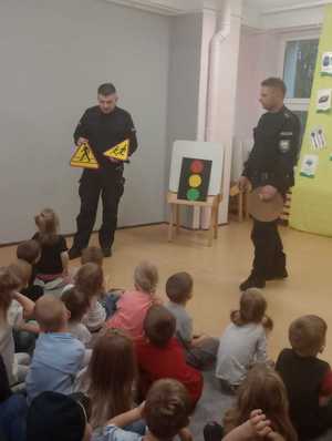 Dwóch umundurowanych policjantów prezentujący znaki drogowe.