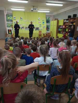 Policjanci podczas prelekcji. Dzieci siedzący i słuchający policjantów