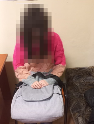 kobieta siedzi na krześle, na kolanach trzyma torbę