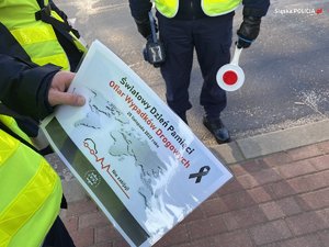 na zdjęciu policjant trzyma w ręce informator z napisem &lt;światowy dzień pamięci ofiar wypadków drogowych&gt;