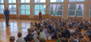 na zdjęciu uczniowie szkoły w sali gimnastycznej w trakcie spotkania z policjantem