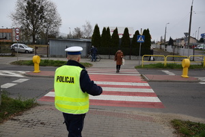 na zdjęciu policjant obserwuje przejście dla pieszych, przez które idzie osoba