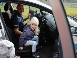na zdjęciu dziecko w policyjnym radiowozie, w którym siedzi także policjant