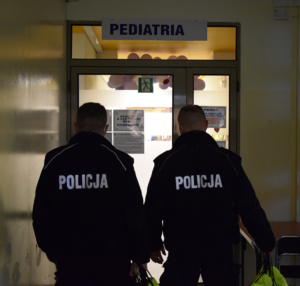 Na zdjęciu widoczni policjanci przed wejściem na odział pediatrii